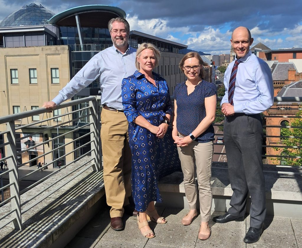 Four people standing on balcony.