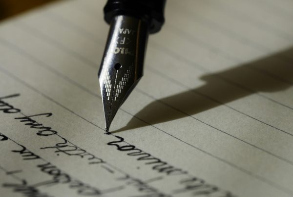 Image shows nib of pen writing on lined paper