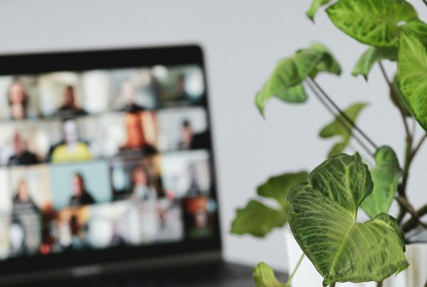 laptop with people on a screen having a meeting.